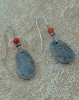 Handmade earrings with smooth gray pebbles, accented with red agate and hematite beads on silver hooks.