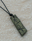 A handmade black and green pendant with a textured design, attached to an adjustable black cord, unique design personally crafted in Kea.