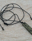 A handmade black and green pendant with a textured design, attached to an adjustable black cord, unique design personally crafted in Kea.