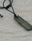 A handmade black and green pendant with a textured design, attached to an adjustable black cord, unique design personally crafted in Kea.