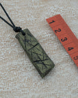 A handmade black and green pendant with a textured design, attached to an adjustable black cord, unique design personally crafted in Kea.