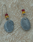 Handmade earrings with smooth gray pebbles, accented with red and yellow agate beads on silver hooks.