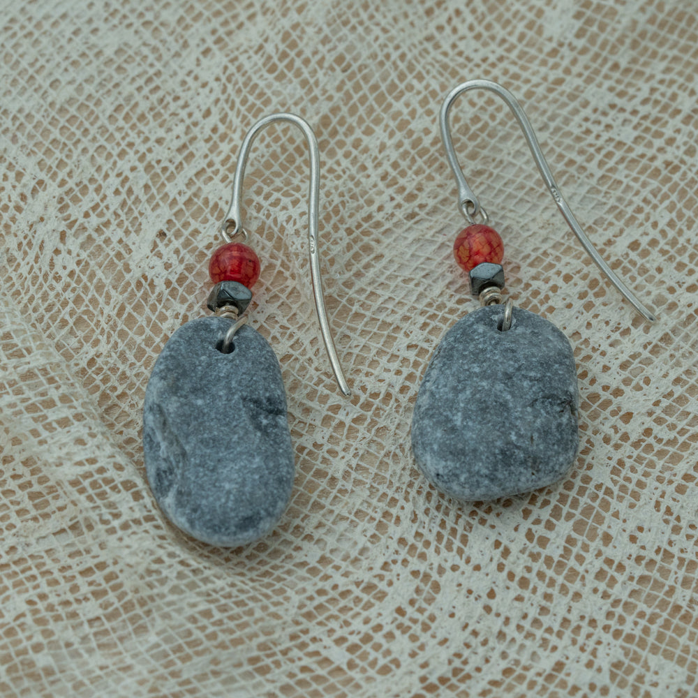 Handmade earrings with smooth gray pebbles, accented with red agate and hematite beads on silver hooks.