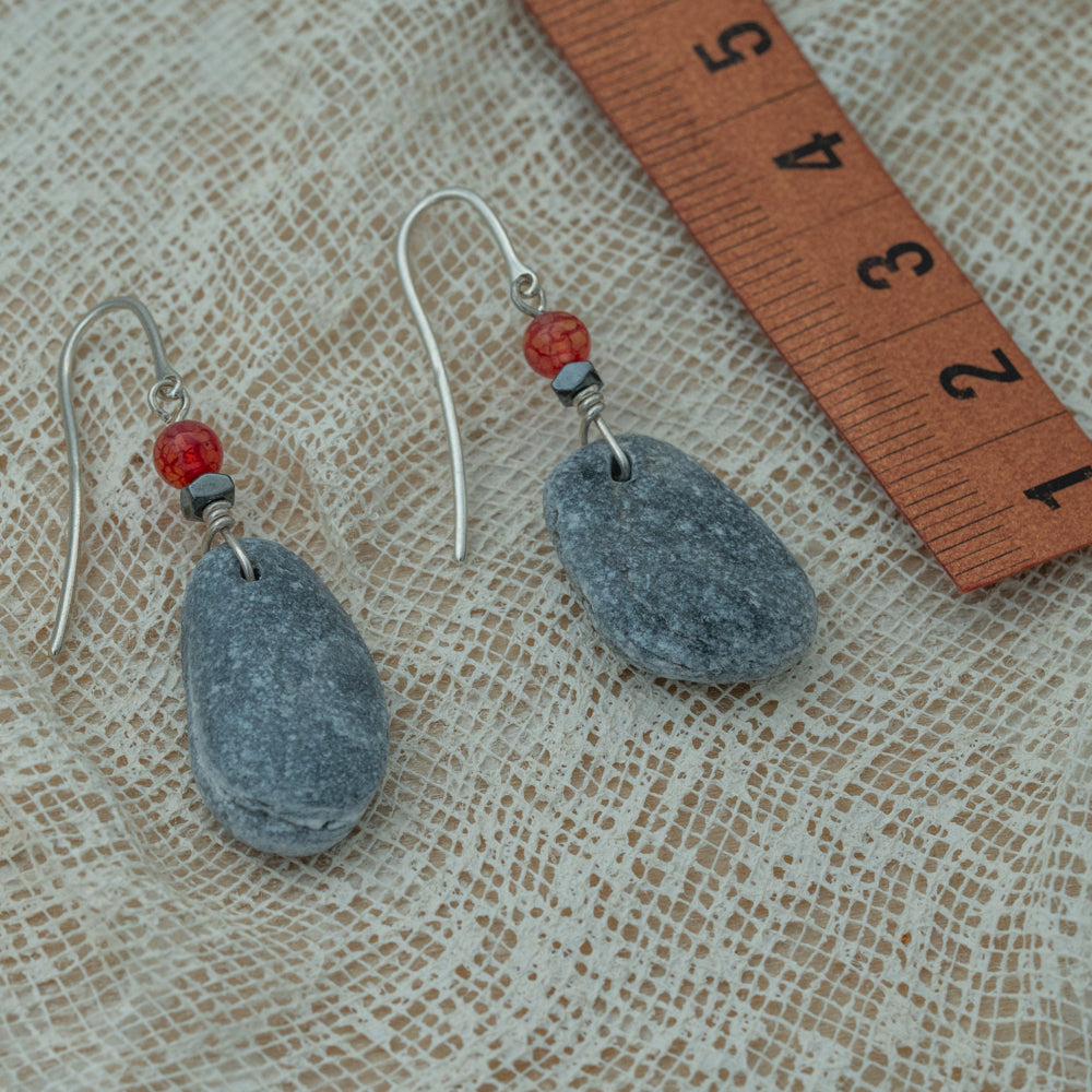 Handmade earrings with smooth gray pebbles, accented with red agate and hematite beads on silver hooks.